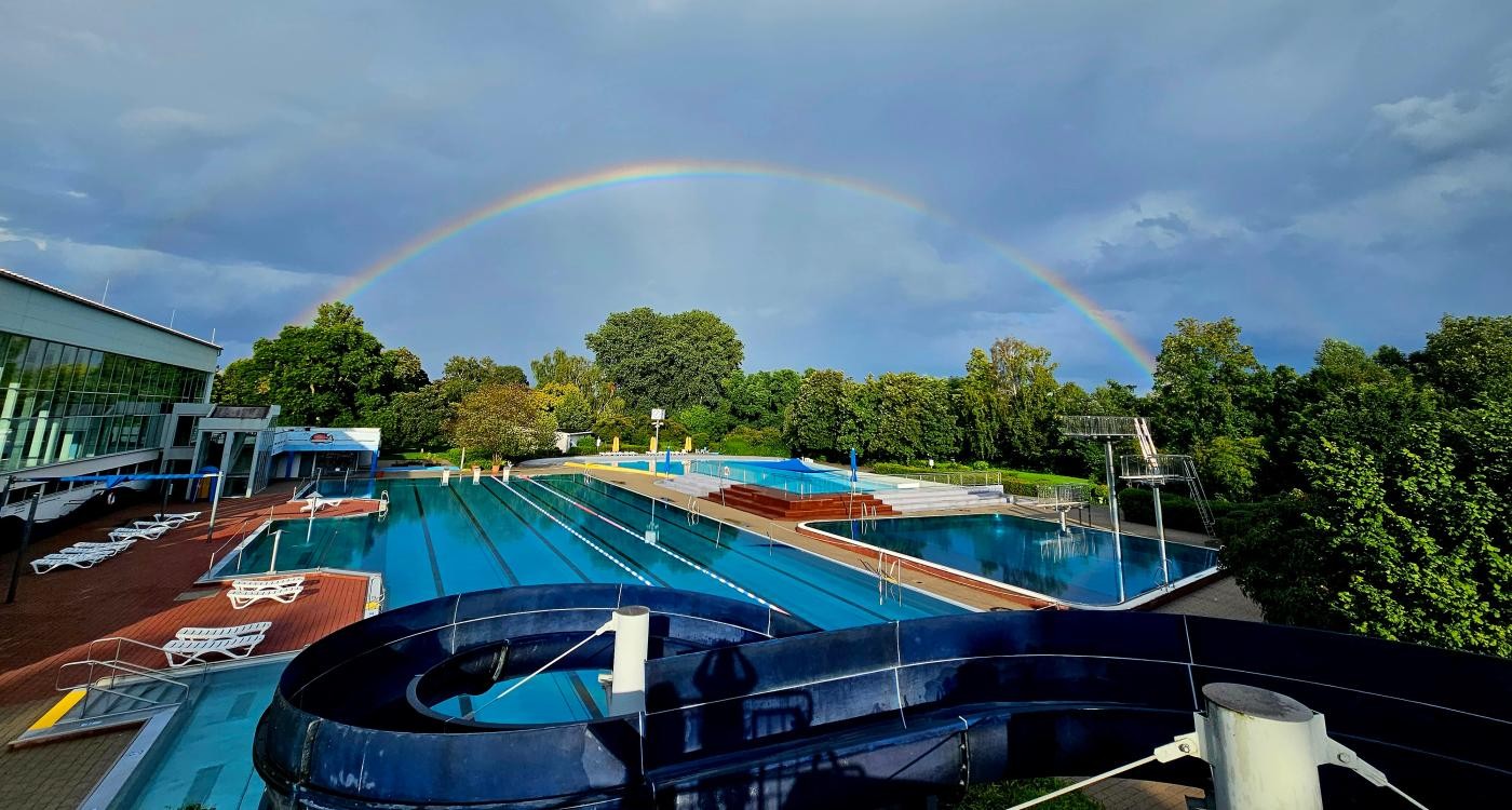 Schwimmbecken mit Regenbogen im Hintergrund