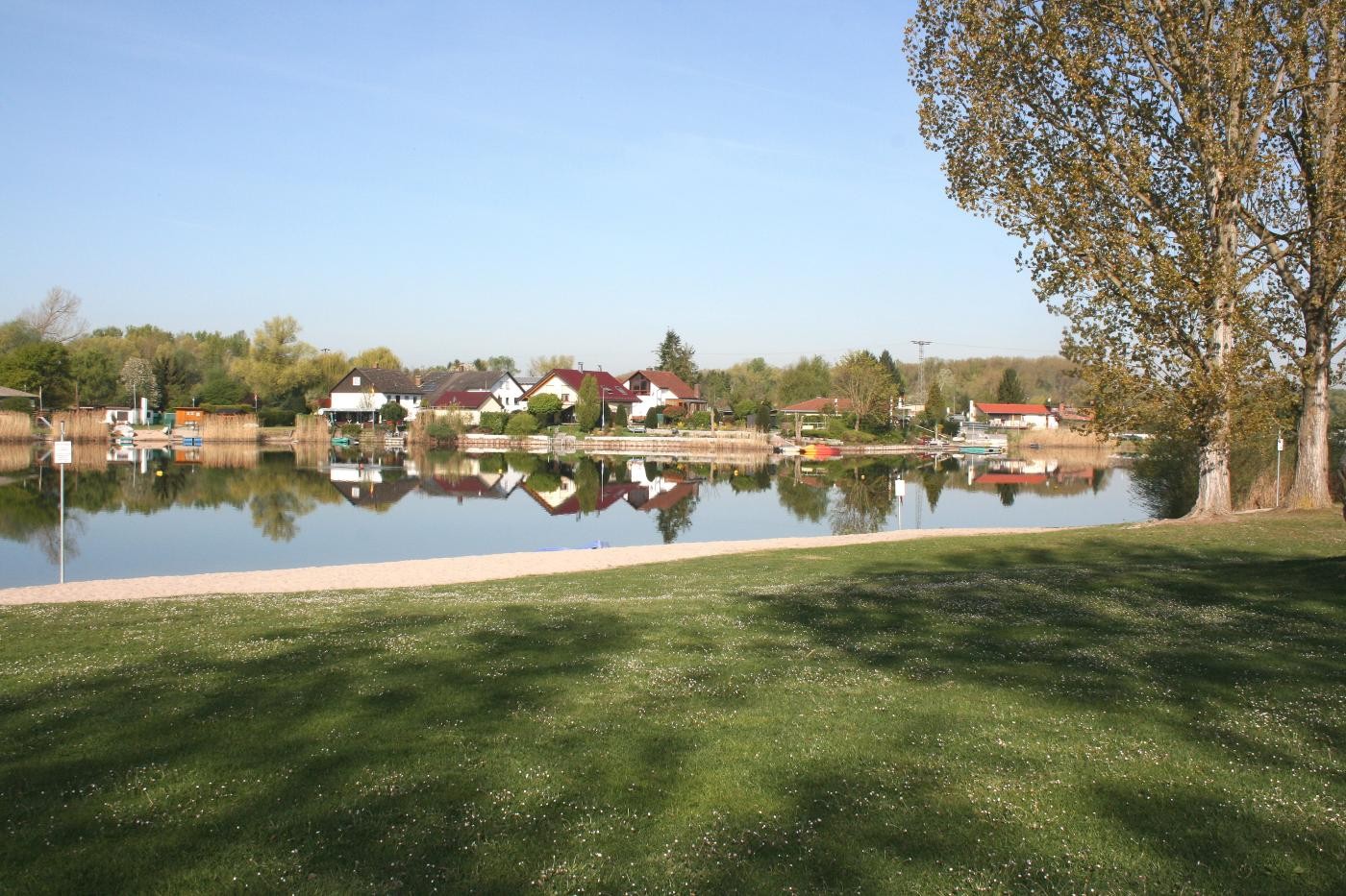 Liegewiese mit See und Häusern am Ufer im Hintergrund