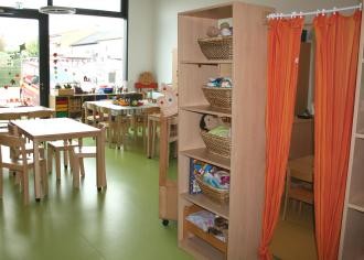 Betreuungszimmer mit Tischen, Stühlen und Regalen
