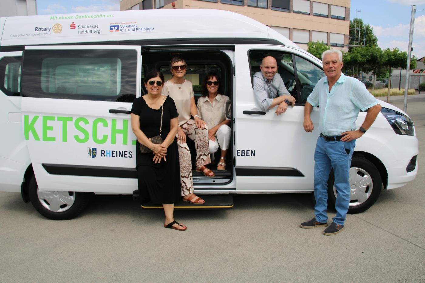Verwaltungsmitarbeitende und Sponsoren stehen beim Bus